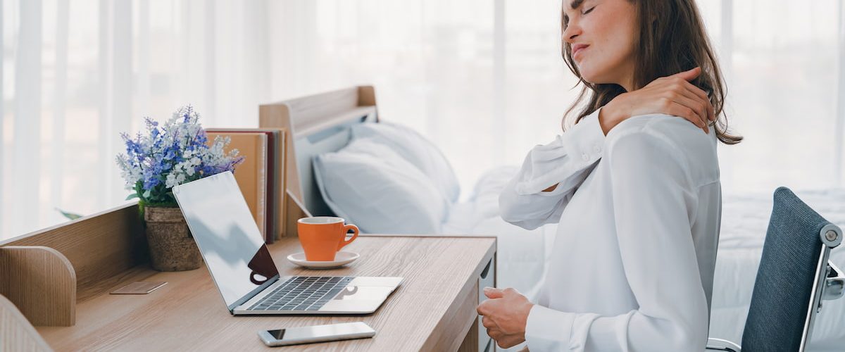  A lady rubbing her back after sitting for to long at a computer desk